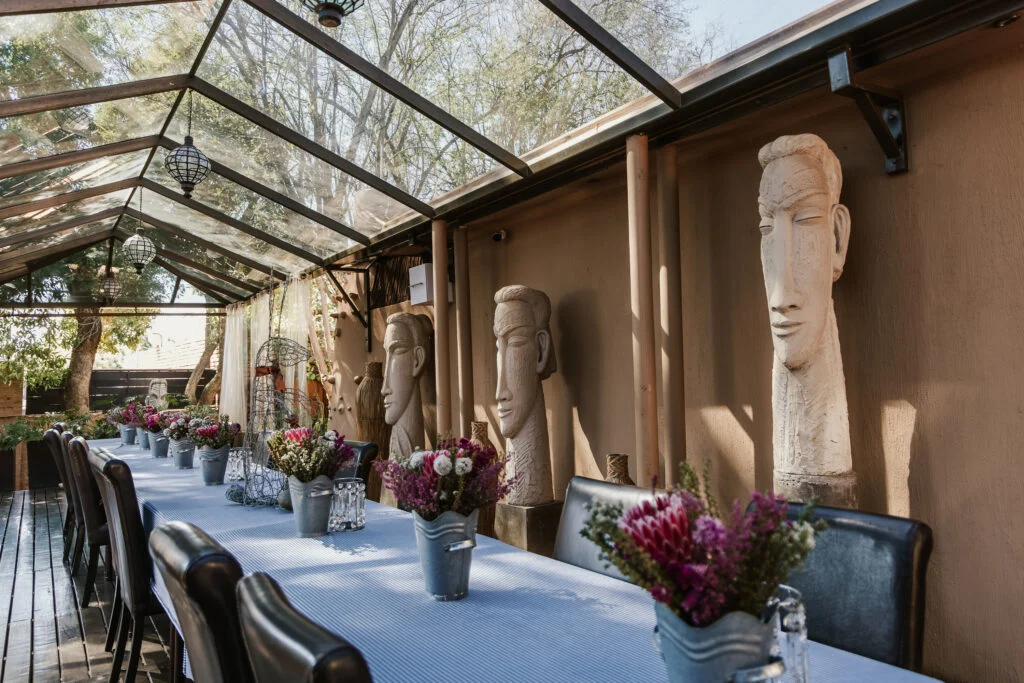 Long dining table beneath the glass-roofed conservatory at Casa Kaya.